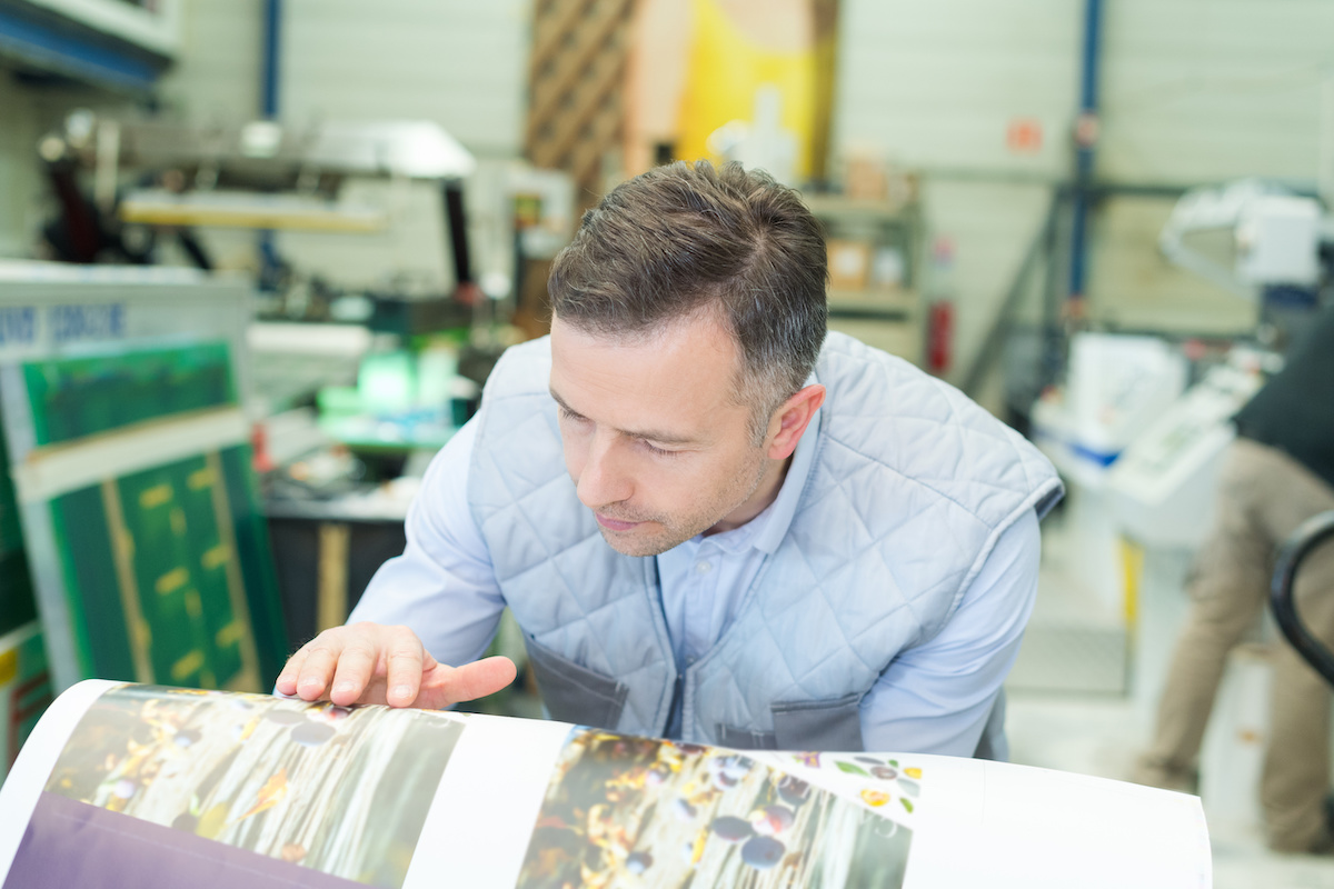 printing press supervisor checking the quality of prints